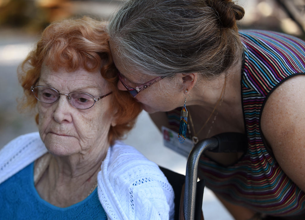 Wanda Hoffman whispers a type of object in Flora Toalson's ear